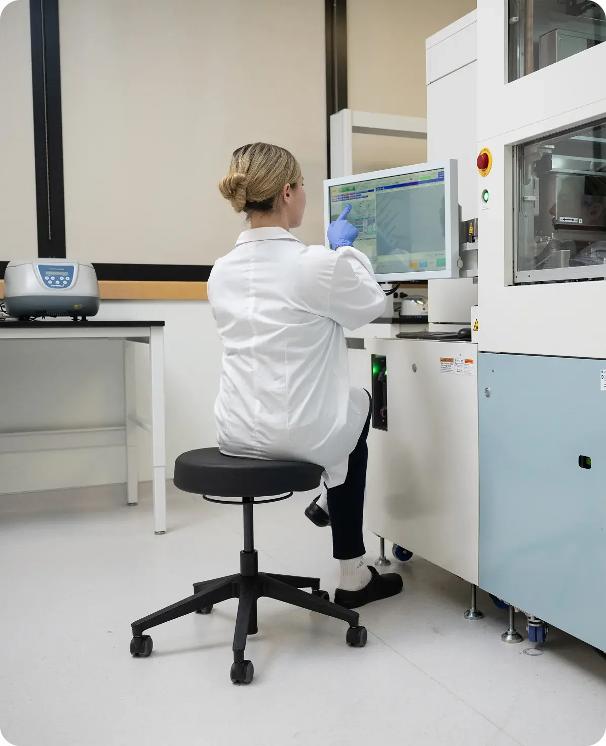 Researcher operating the NPi-11 automated cell culture system in a laboratory, using the touchscreen interface to design iPSC protocols